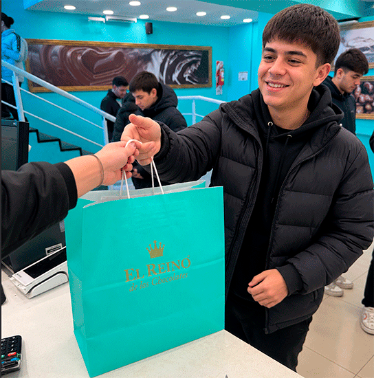 Egresado recibiendo feliz su bolsa de El Reino de los Chocolates en la caja